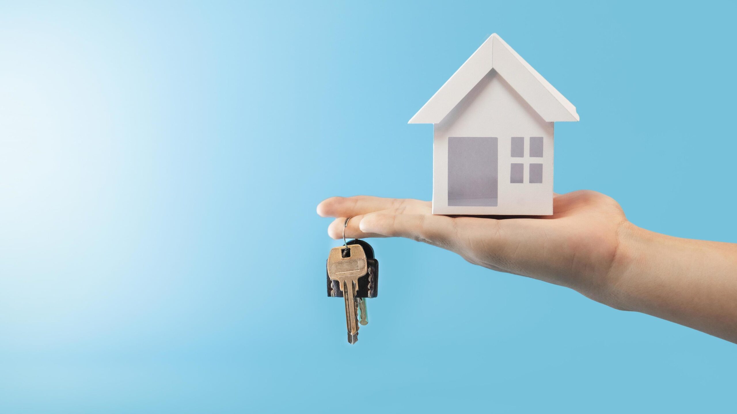 hand-holding-keys-and-house-model-in-blue-background-for-refinance-plan-and-real-estate-concept-free-photo