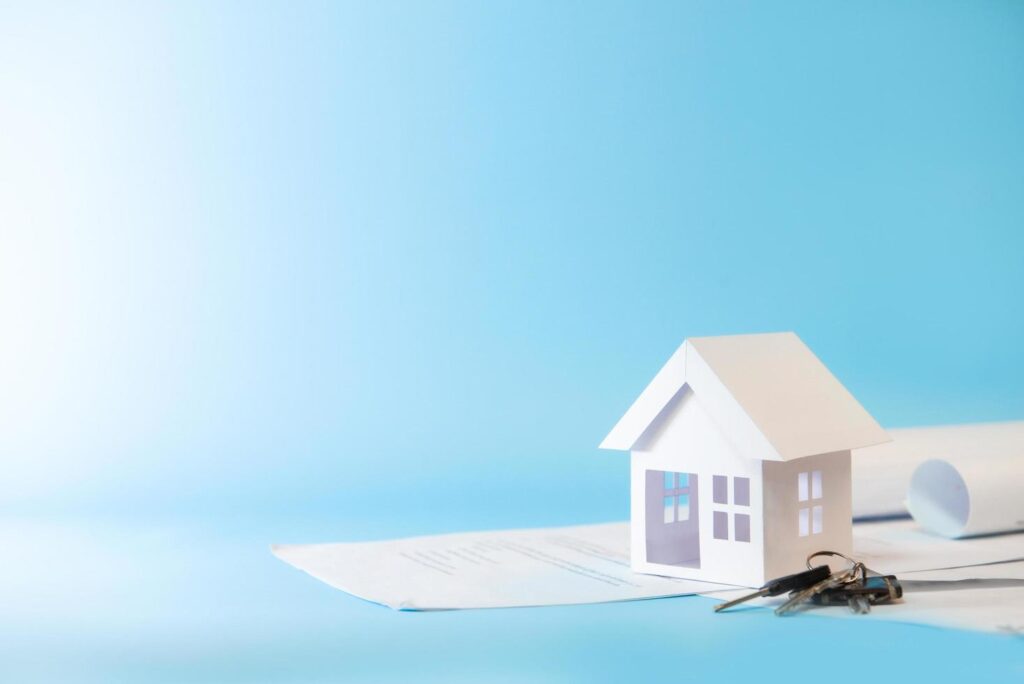 white-house-model-on-trading-documents-with-keys-in-blue-background-for-refinance-plan-and-real-estate-concept-free-photo